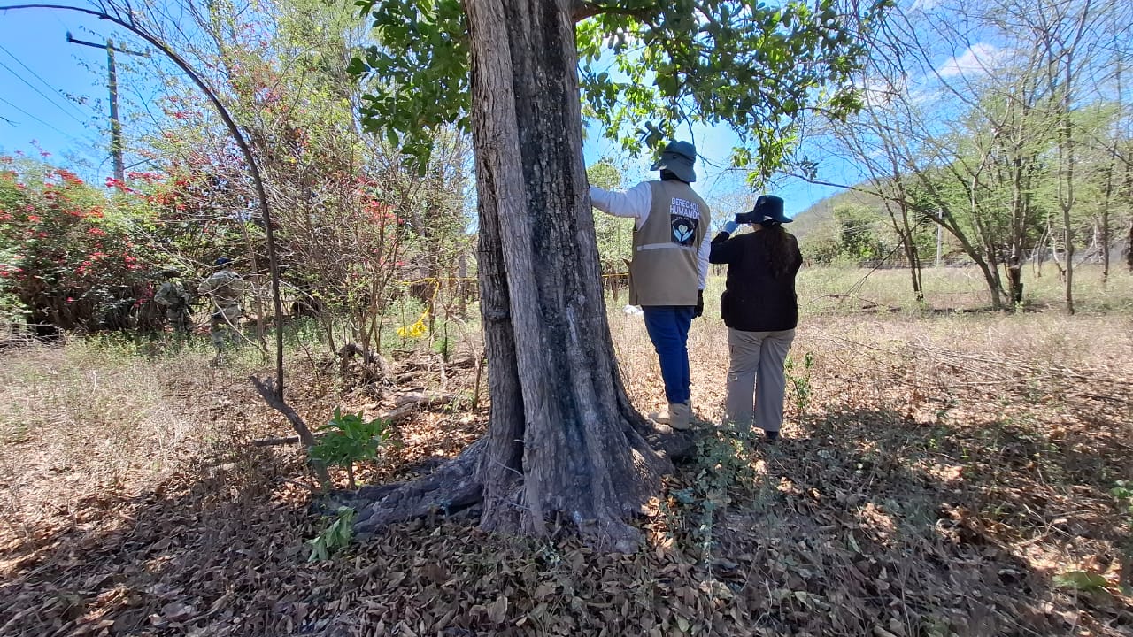 Dos mujeres en un terreno con árboles y maleza