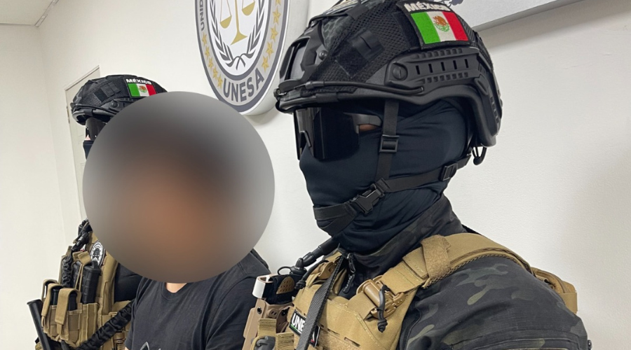Autoridades de seguridad al lado de un detenido con la cara blureada