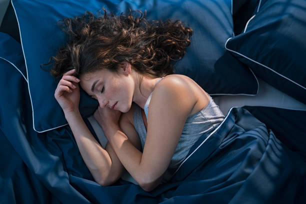 Mujer dormida en una cama con sabanas azules