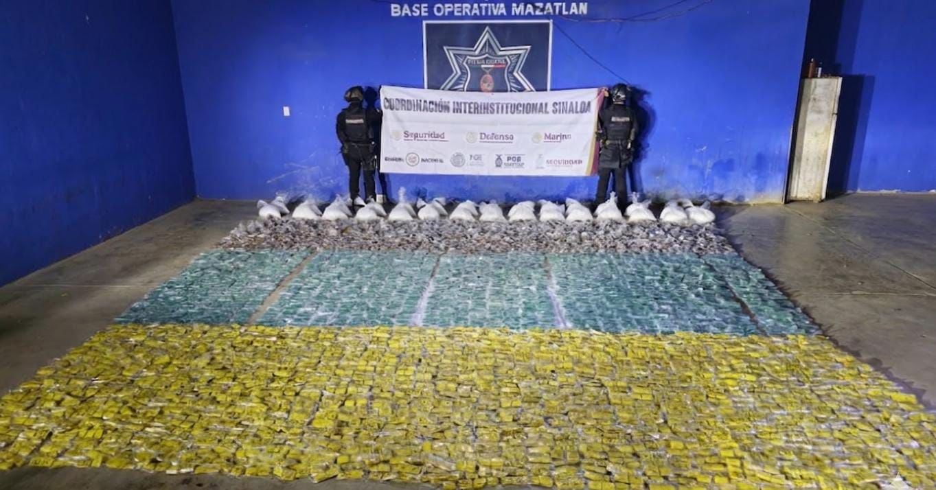 Paquetes y bolsas en el suelo y al fondo dos elementos de seguridad sosteniendo una lona