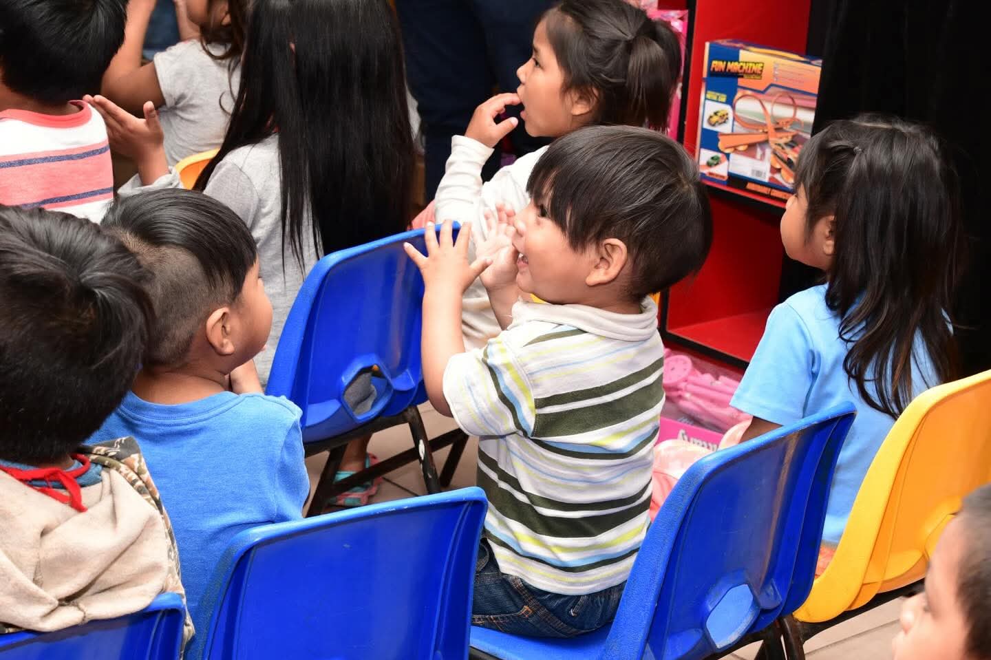Niño de kínder aplaudiendo en una silla pequeña