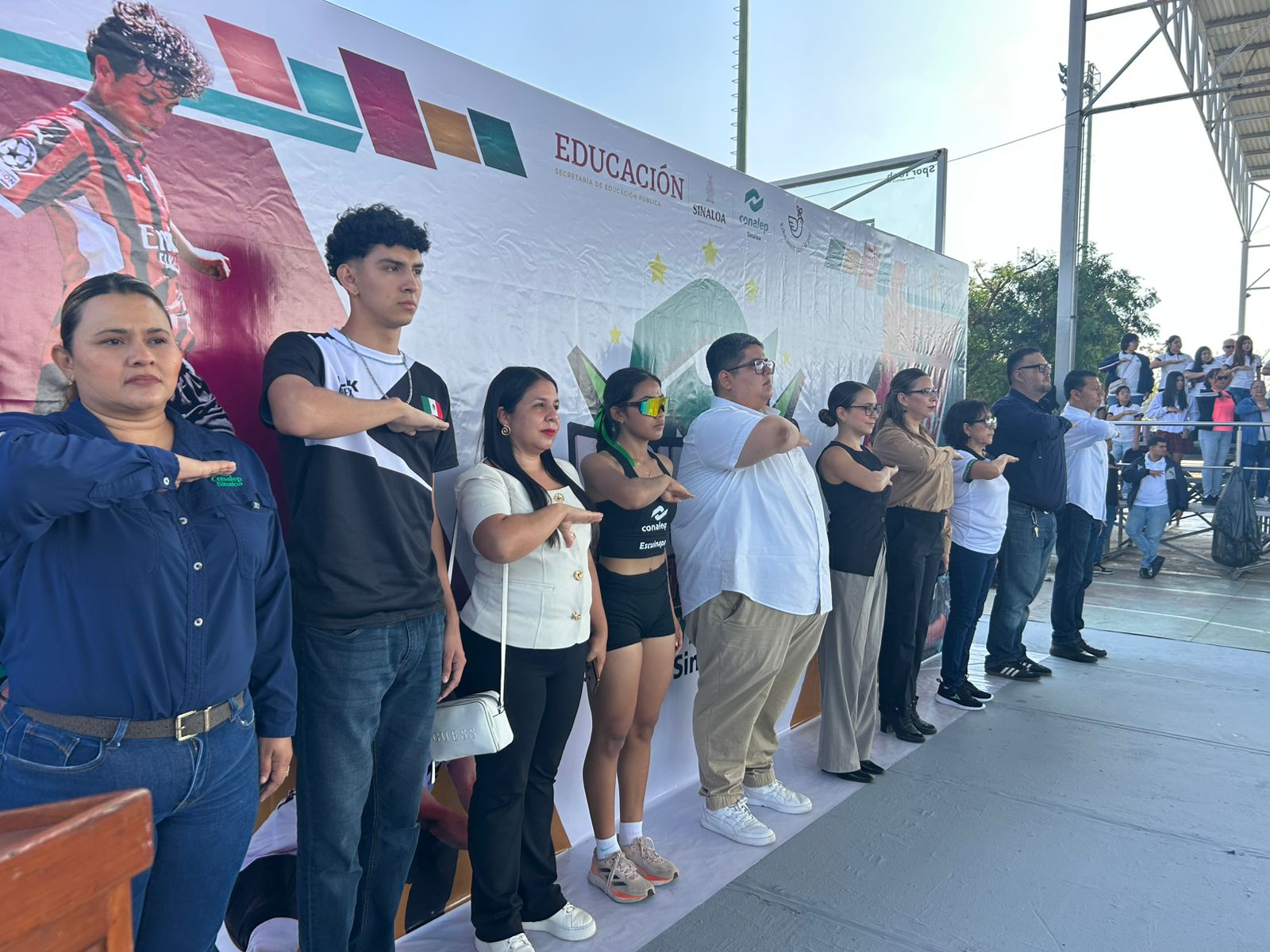 Grupo de personas saludando a la bandera en evento
