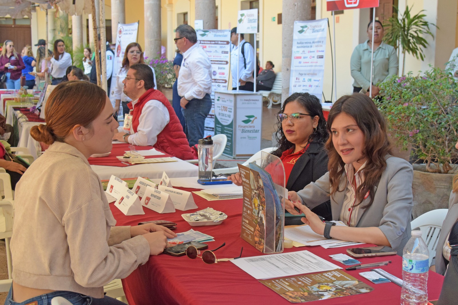Personas sentadas en una mesa con carpetas y documentos