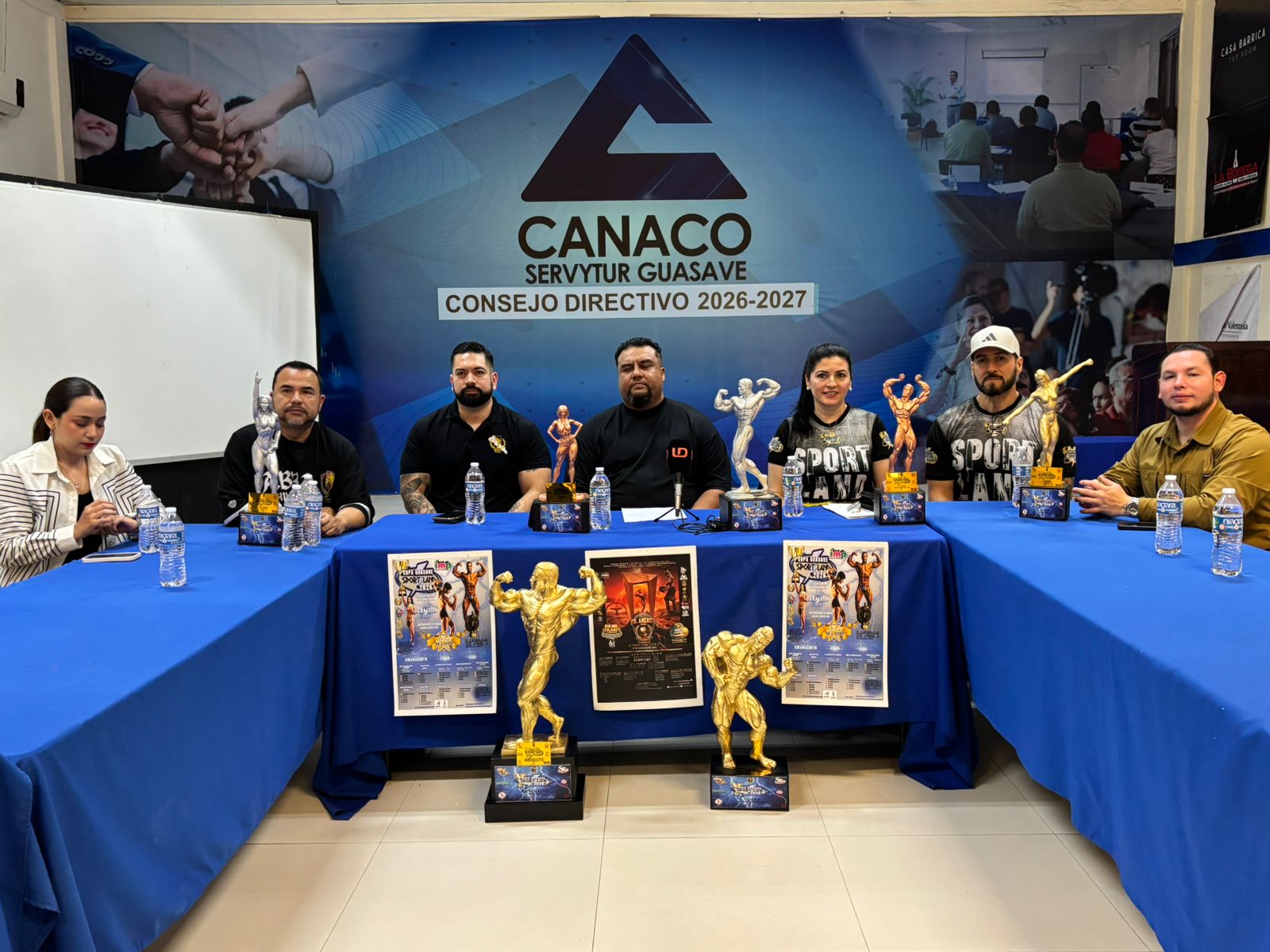 personas sentadas detrás de mesa con trofeos