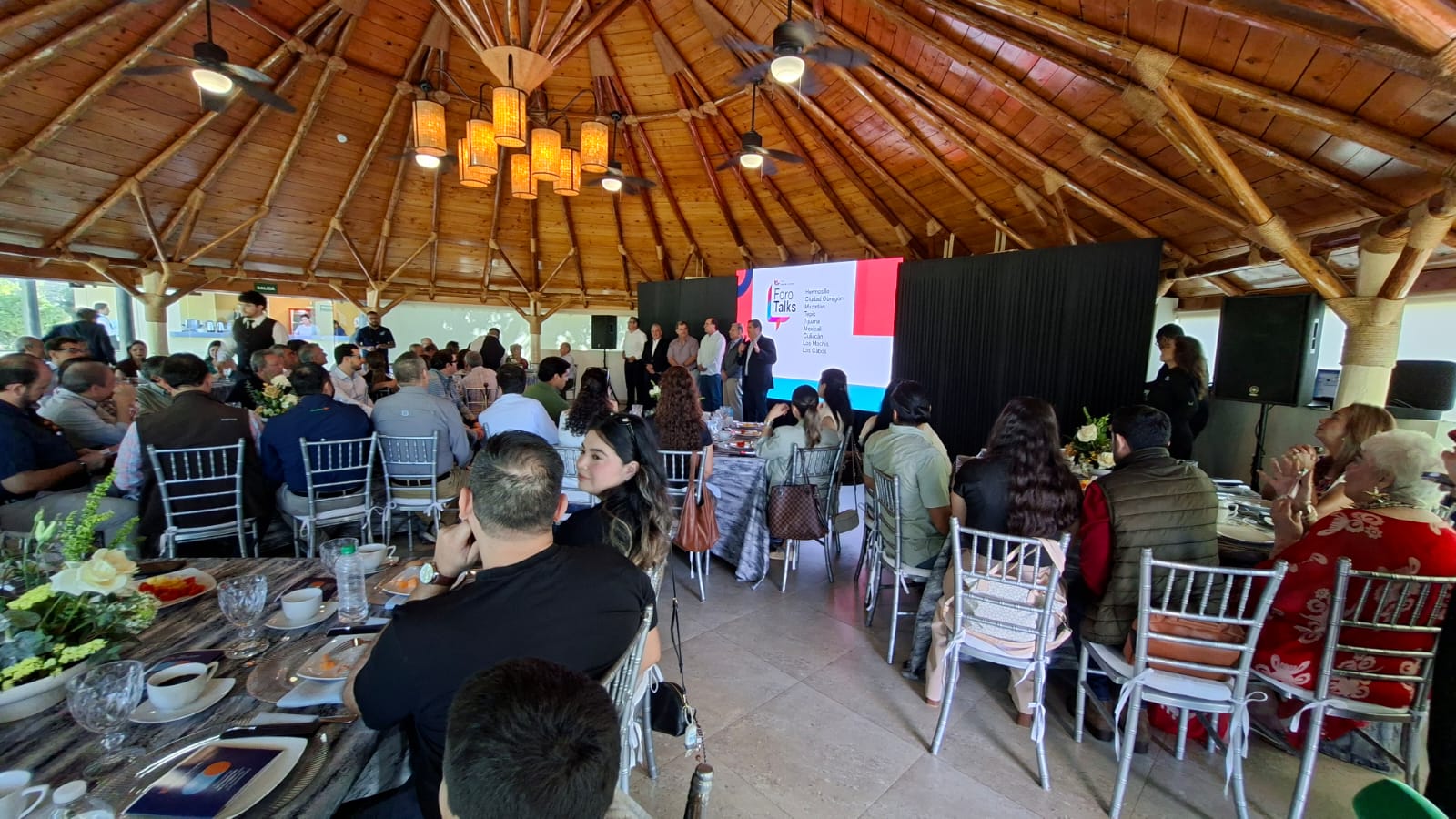 Personas en un evento exponiendo con una pantalla con una diapositiva