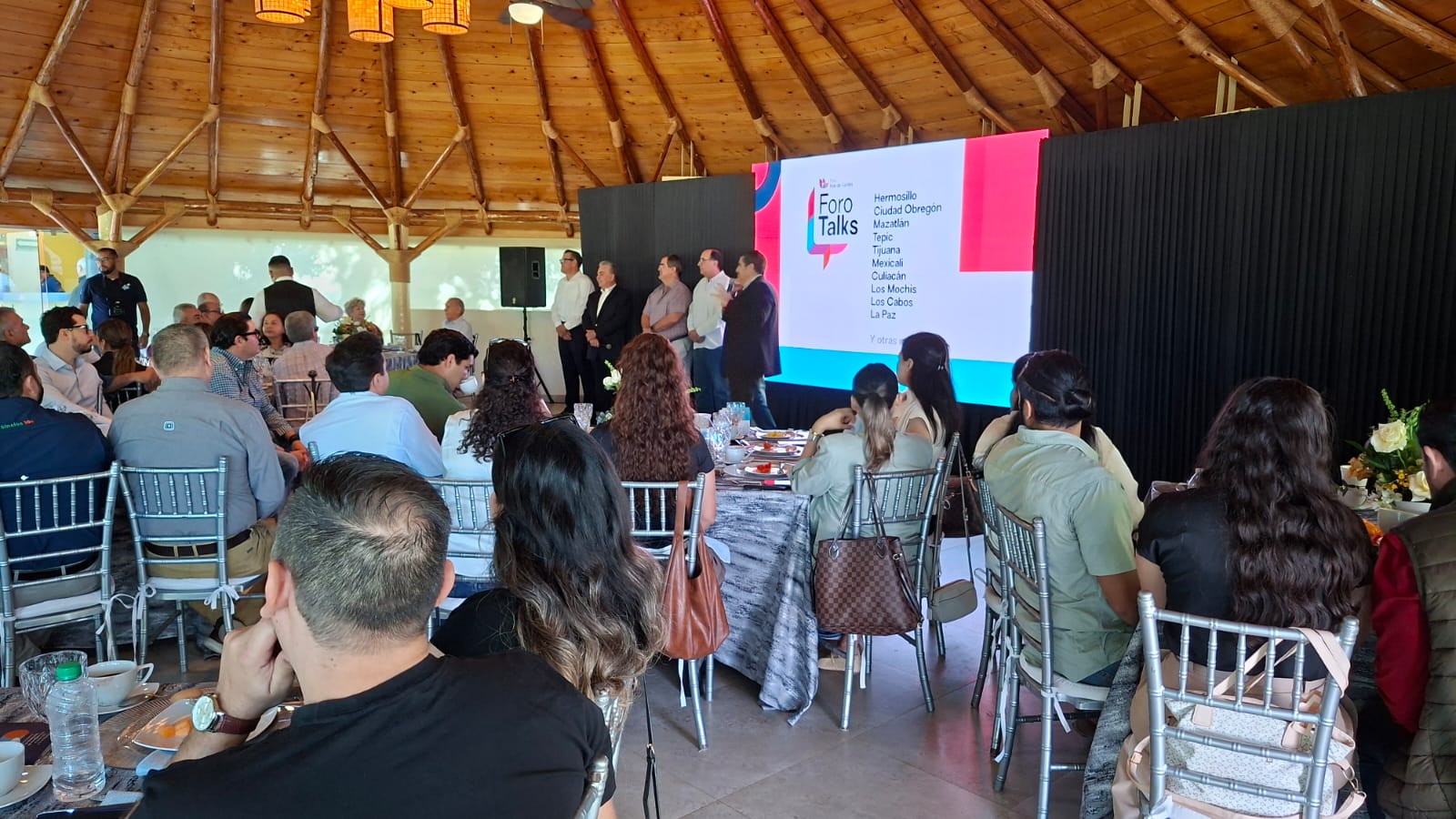 Personas en un evento exponiendo con una pantalla con una diapositiva