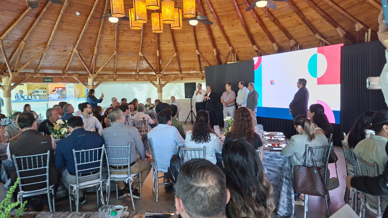 Personas en un evento exponiendo con una pantalla con una diapositiva