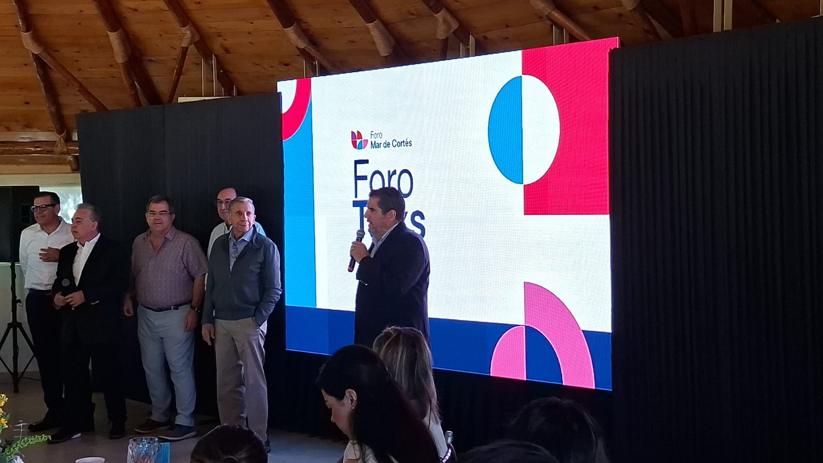 Personas en un evento exponiendo con una pantalla con una diapositiva