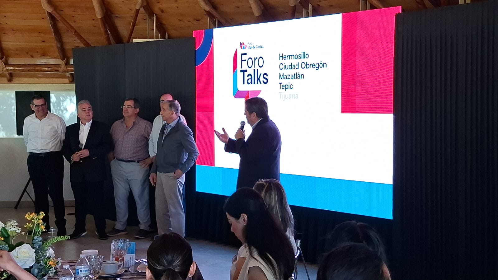PErsonas en una presentación con una diapositiva atrás de ellos