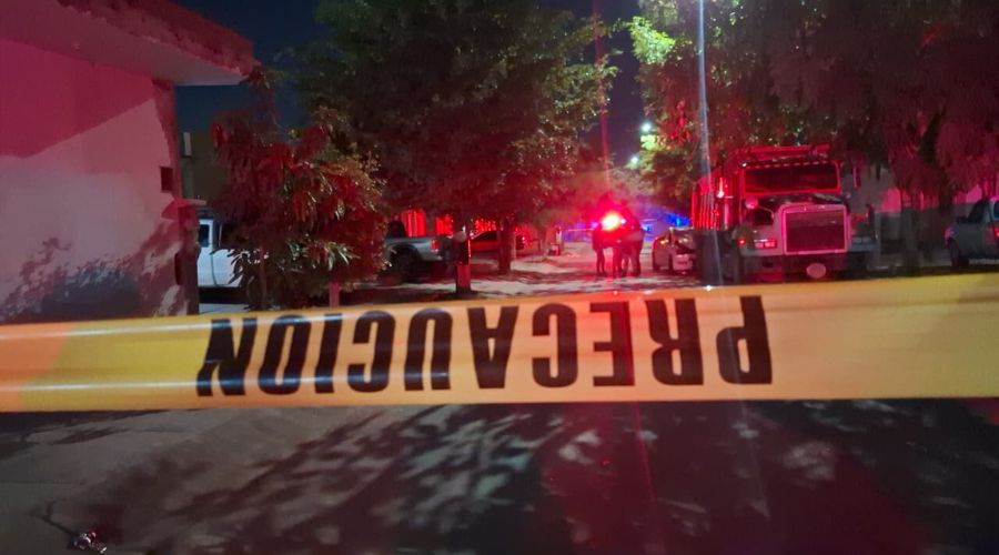 Cinta amarilla de precaució en una calle y al fondo una unidad poliociaca con las luces encendidas y elementos desplegados