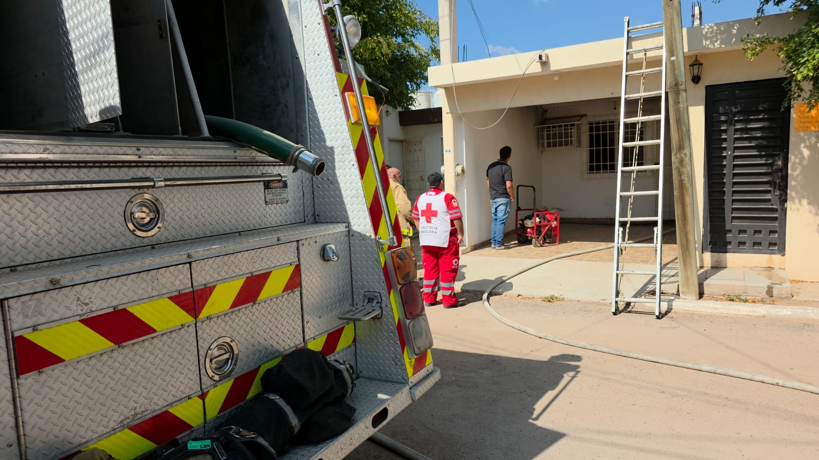 Vivienda con elementos de la cruz roja y bomberos revisando, unidad de bomberos estacionada