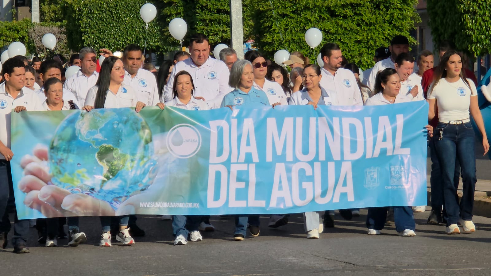 Personas sosteniendo una lona/cartelón con temática del día mundial del agua en una calle durante una marcha