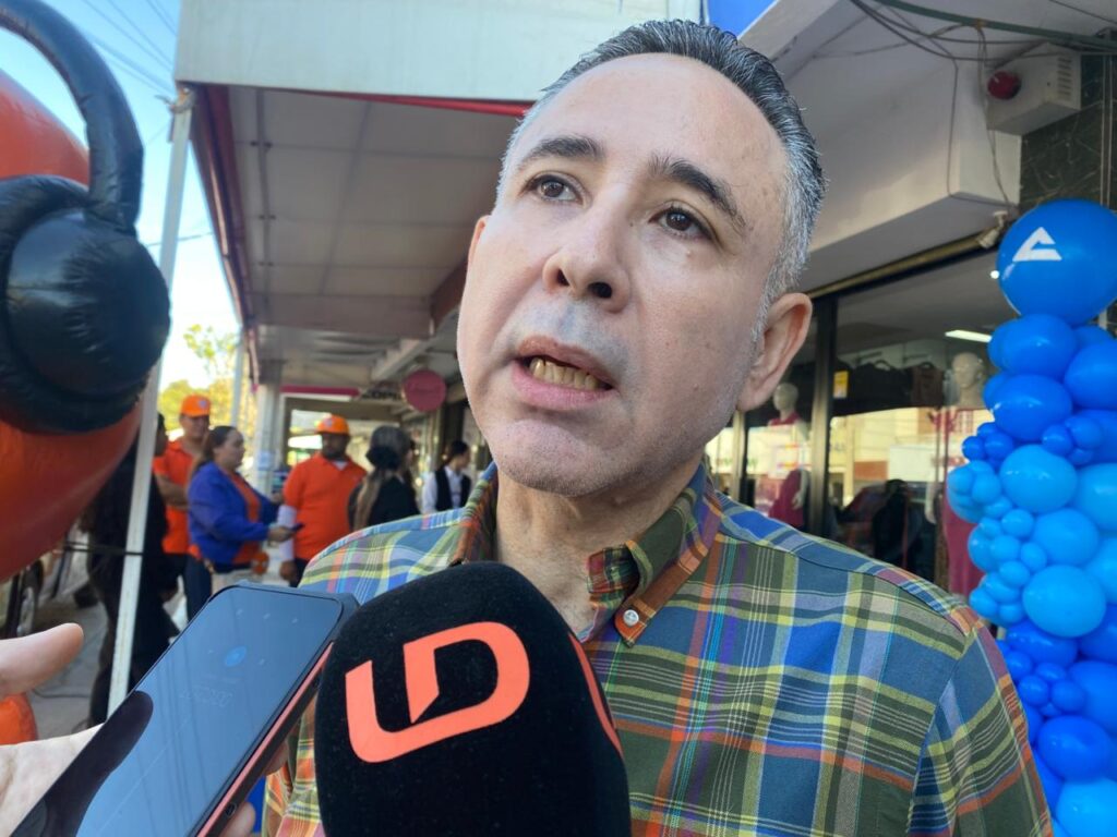 Hombre hablando frente a un micrófono negro con las letras LD en color naranja