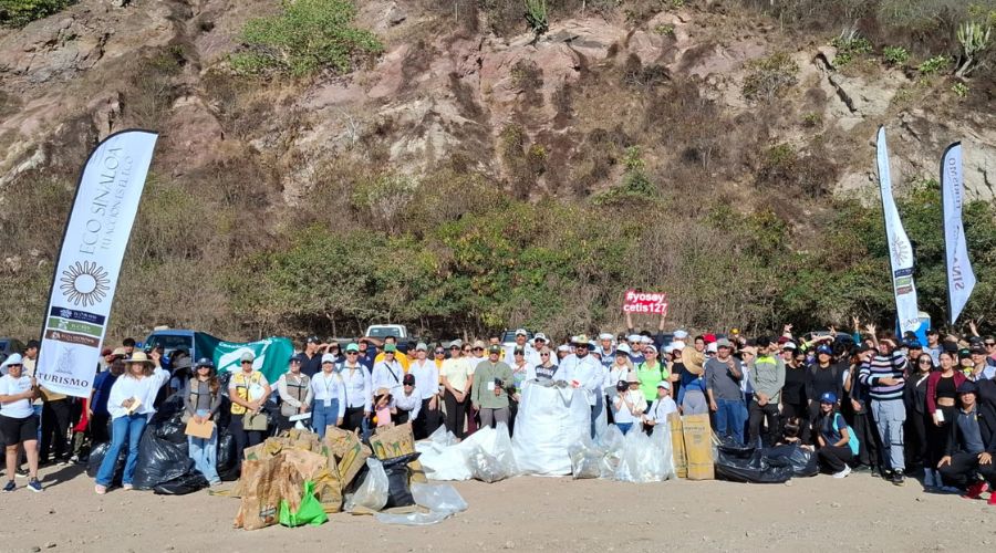 Autoridades y ciudadanía en playa posando para la foto con utensilios de limpieza