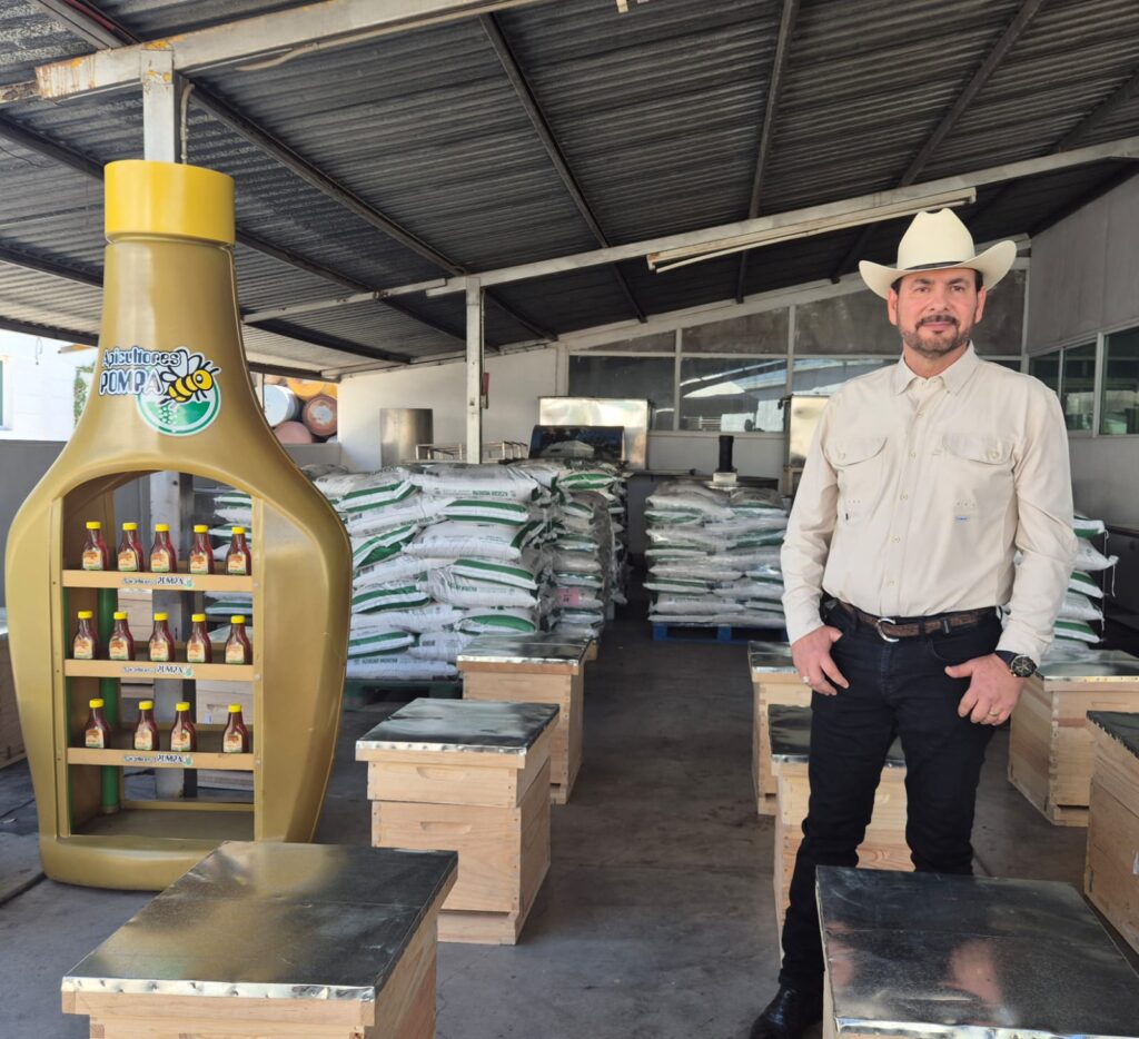 Contenedores de miel en un estante y una persona con sombrero