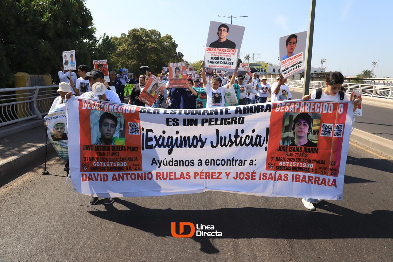 Familiares de José Isaías y David Antonio con pancartas caminando por una calle de Culiacán