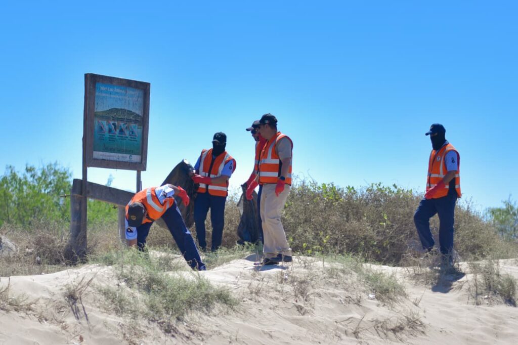 Personas juntando basura en la arena de El Maviri
