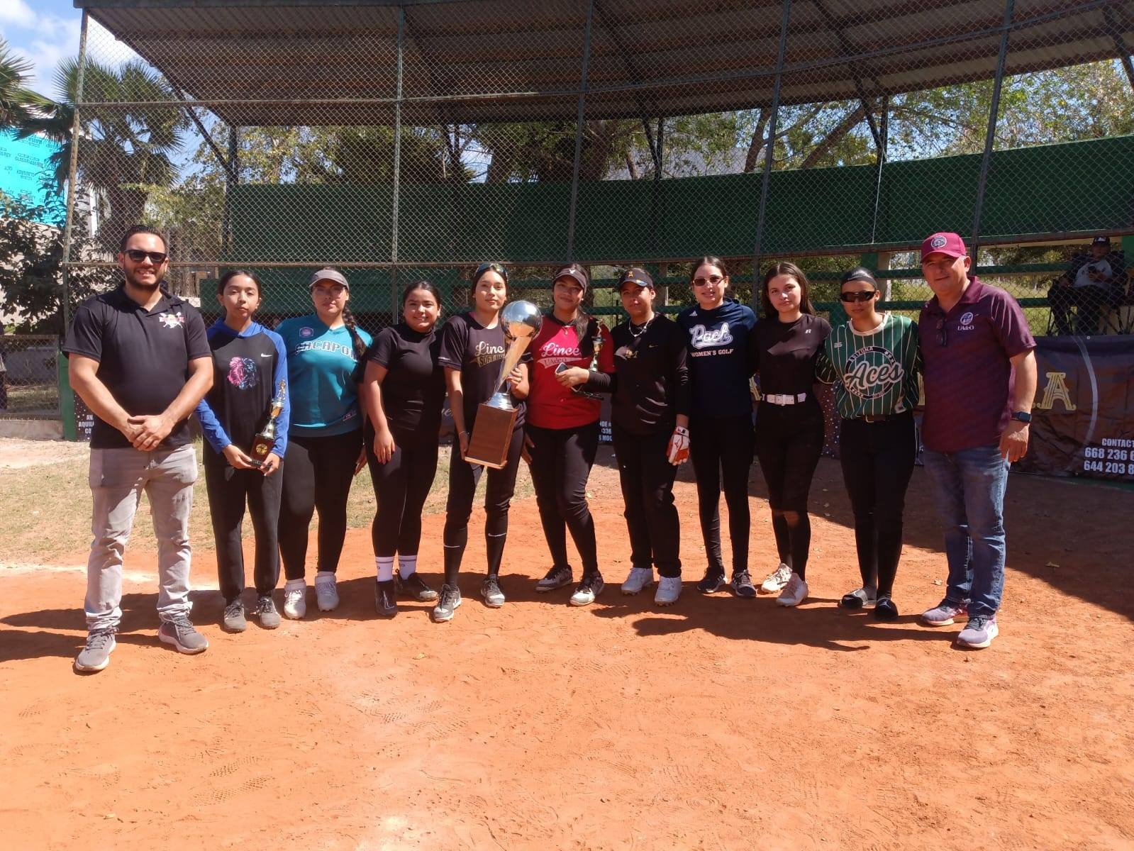 Jugadoras de softbol con trofeo en mano