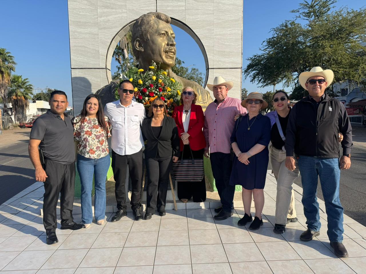 Personas posando para foto enfrente de monumento de Luis Donaldo Colosio
