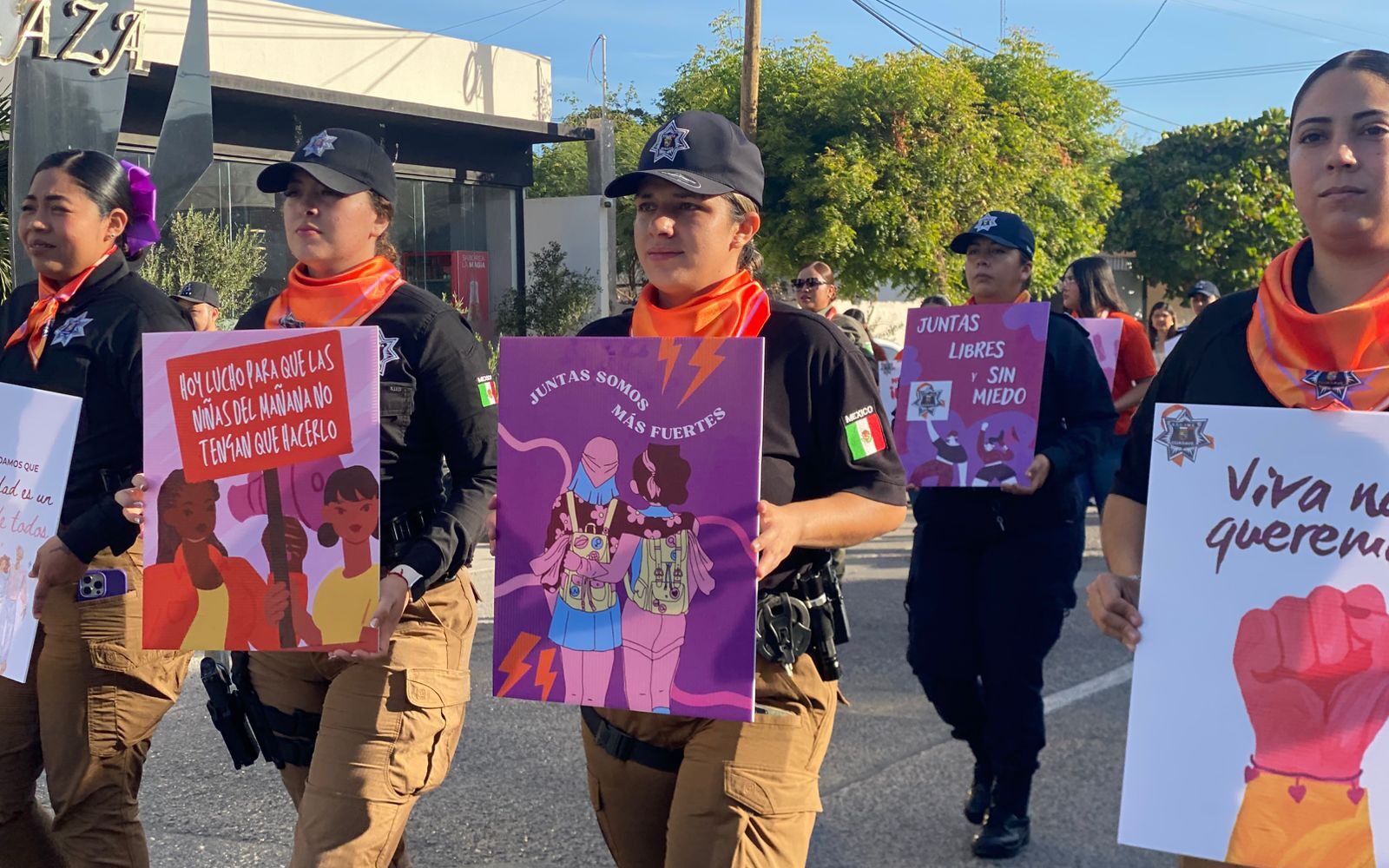 Mujeres policías marchando con carteles alusivos al 8M