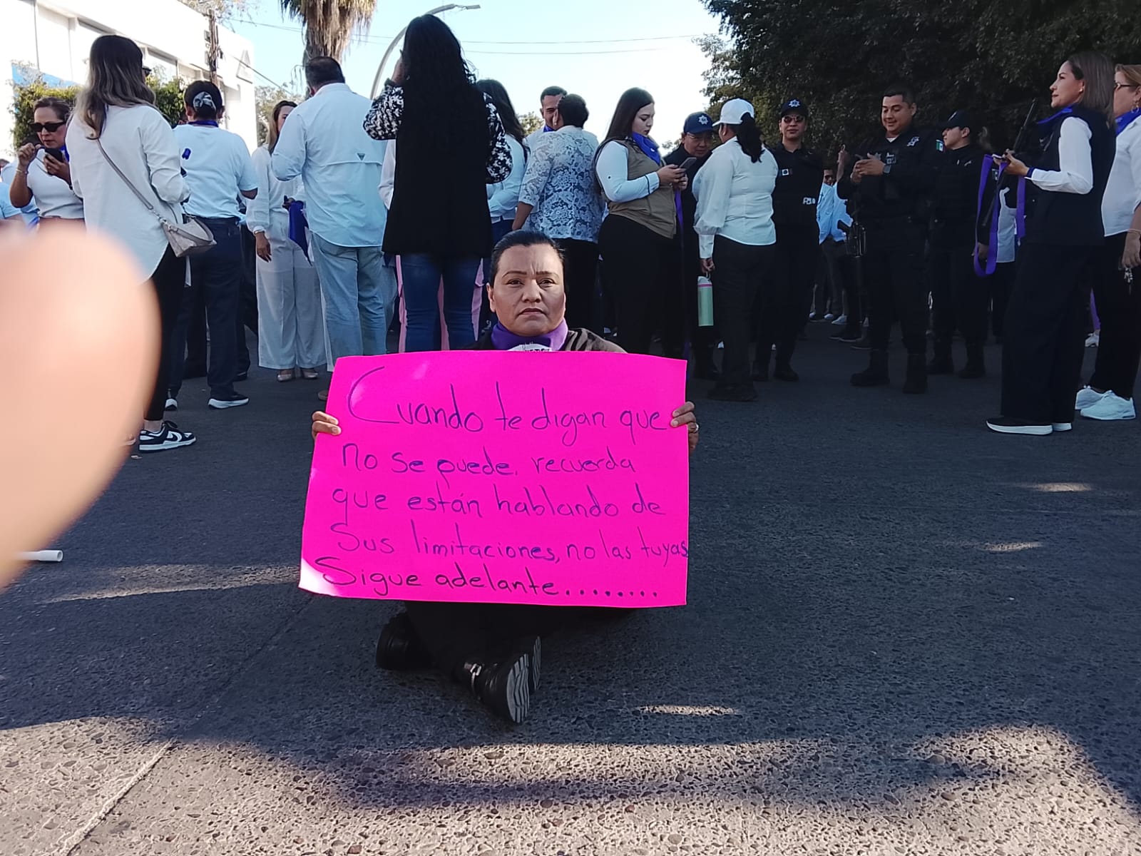Mujer en el suelo sosteniendo una pancarta color rosa