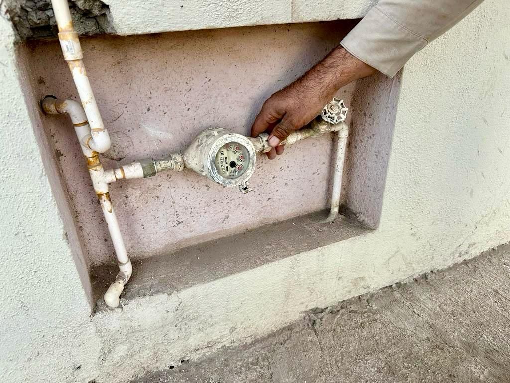 Medidor de agua y mano de una persona sosteniéndolo