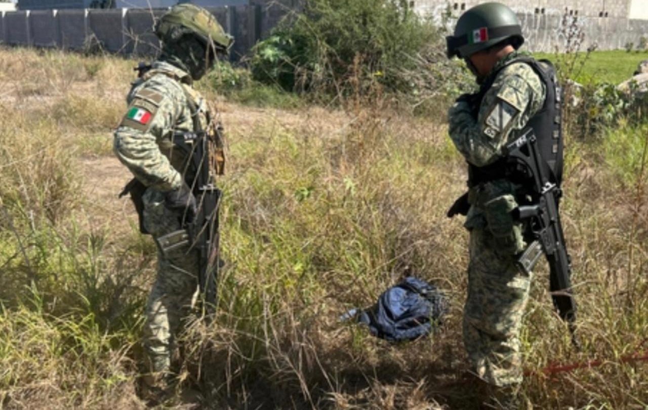 Dos elementos del Ejército Mexicano y en el medio una maleta abandonada entre matorrales