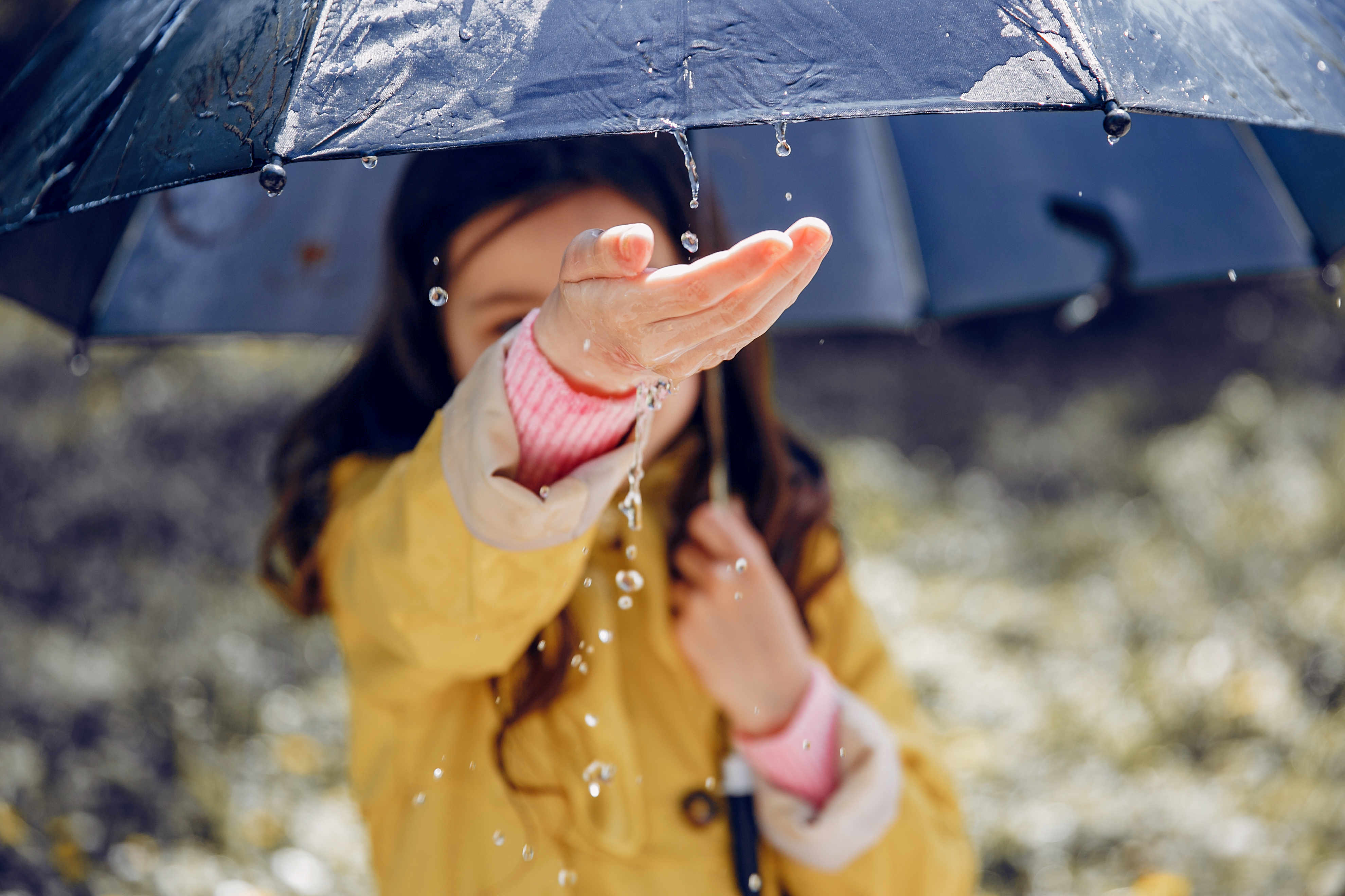 Niña con impermeable. Niña jugando en un parque.