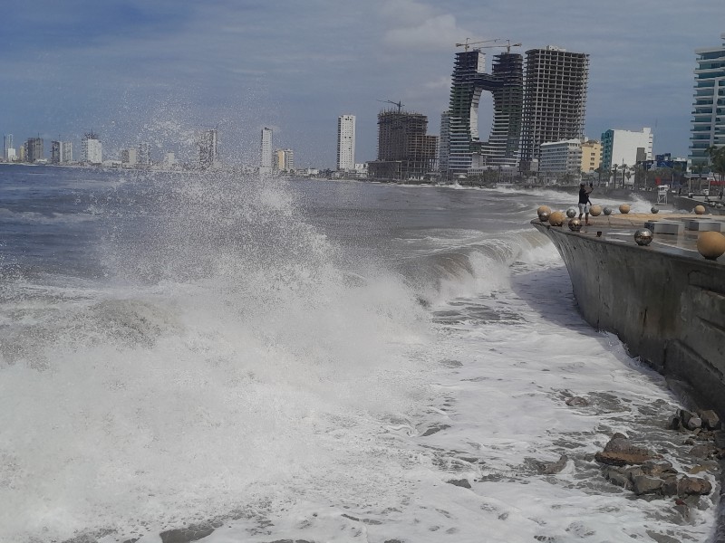 Olas del mar golpeando en la costa y al fondo se observan edificios