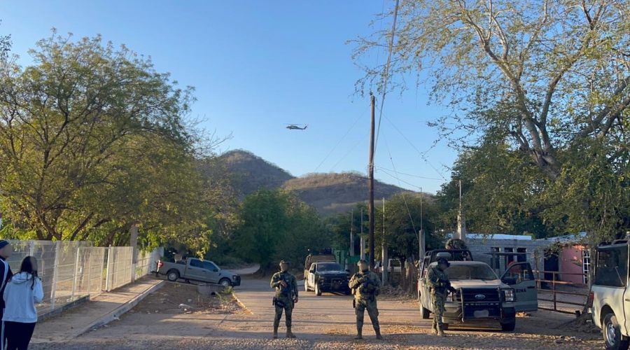 Elementos militares y unidades desplegados por un camino de terracería y un helicoptero en el cielo