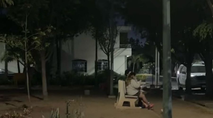 Parque oscuro en Culiacán con una mujer sentada en una banca