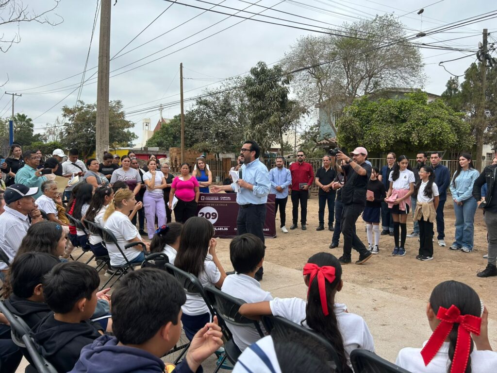 Alcalde de Culiacán hablando en un micrófono con personas sentadas en sillas