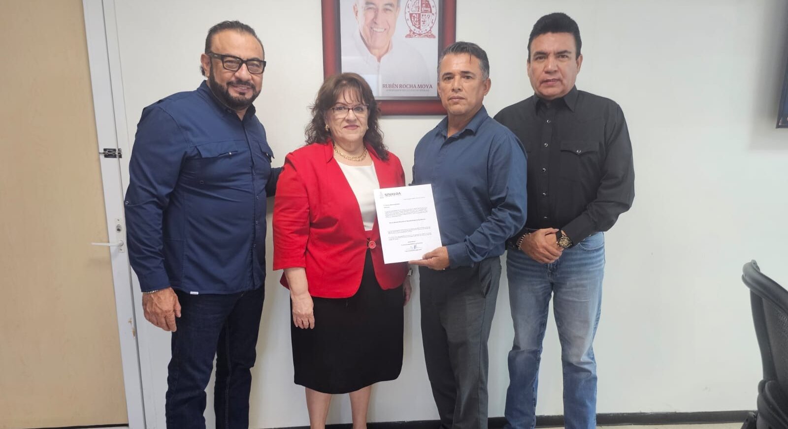 Cuatro personas de pie con un documento