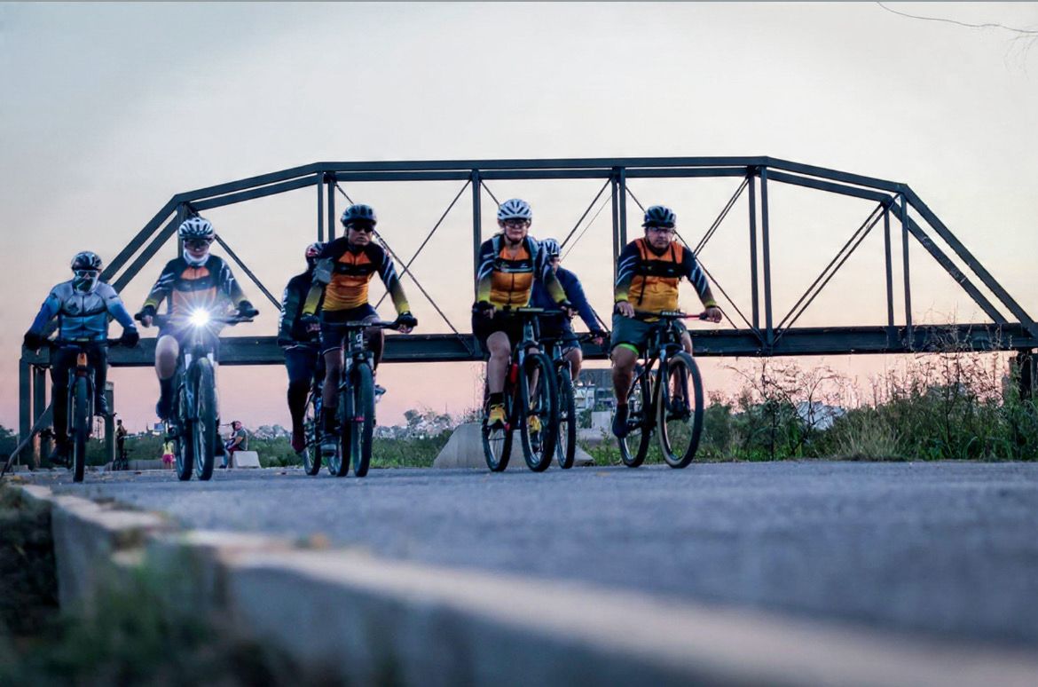 Ciclistas transitando por vialidad detrás un puente