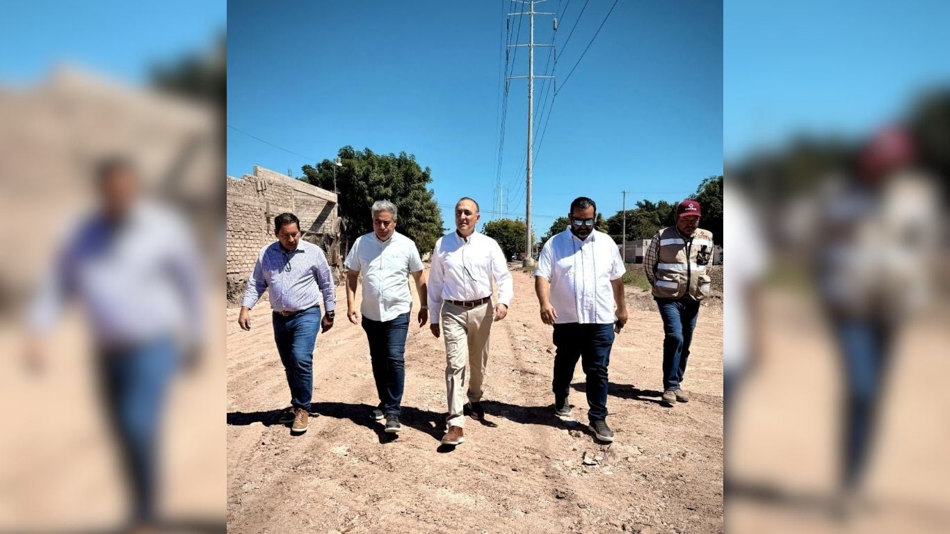 alcalde acompañado caminando por calle de terracería