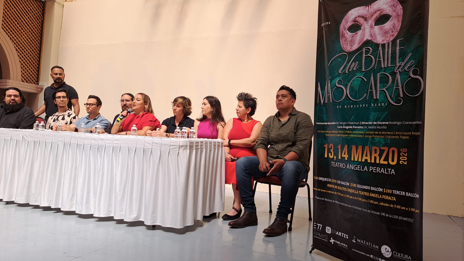 personas sentadas detrás de una mesa sobre un escenario