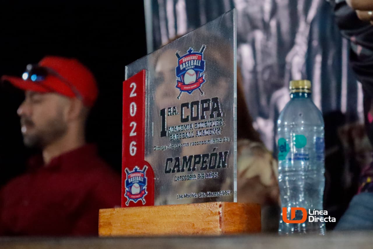 Placa de un torneo en una mesa y personas al fondo