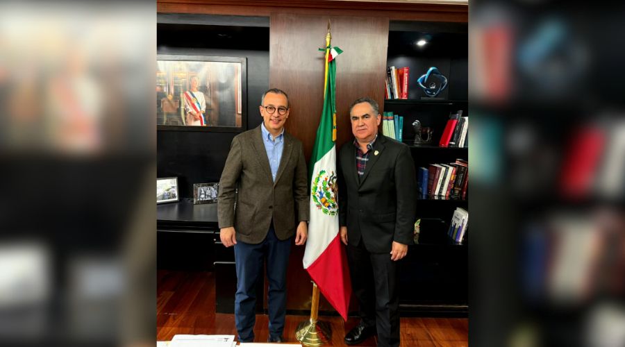 El rector de la UAS, Jesús Madueña Molina el titular de la Dgesui, Carlos Iván Moreno Arellano en una oficina junto a una bandera de México