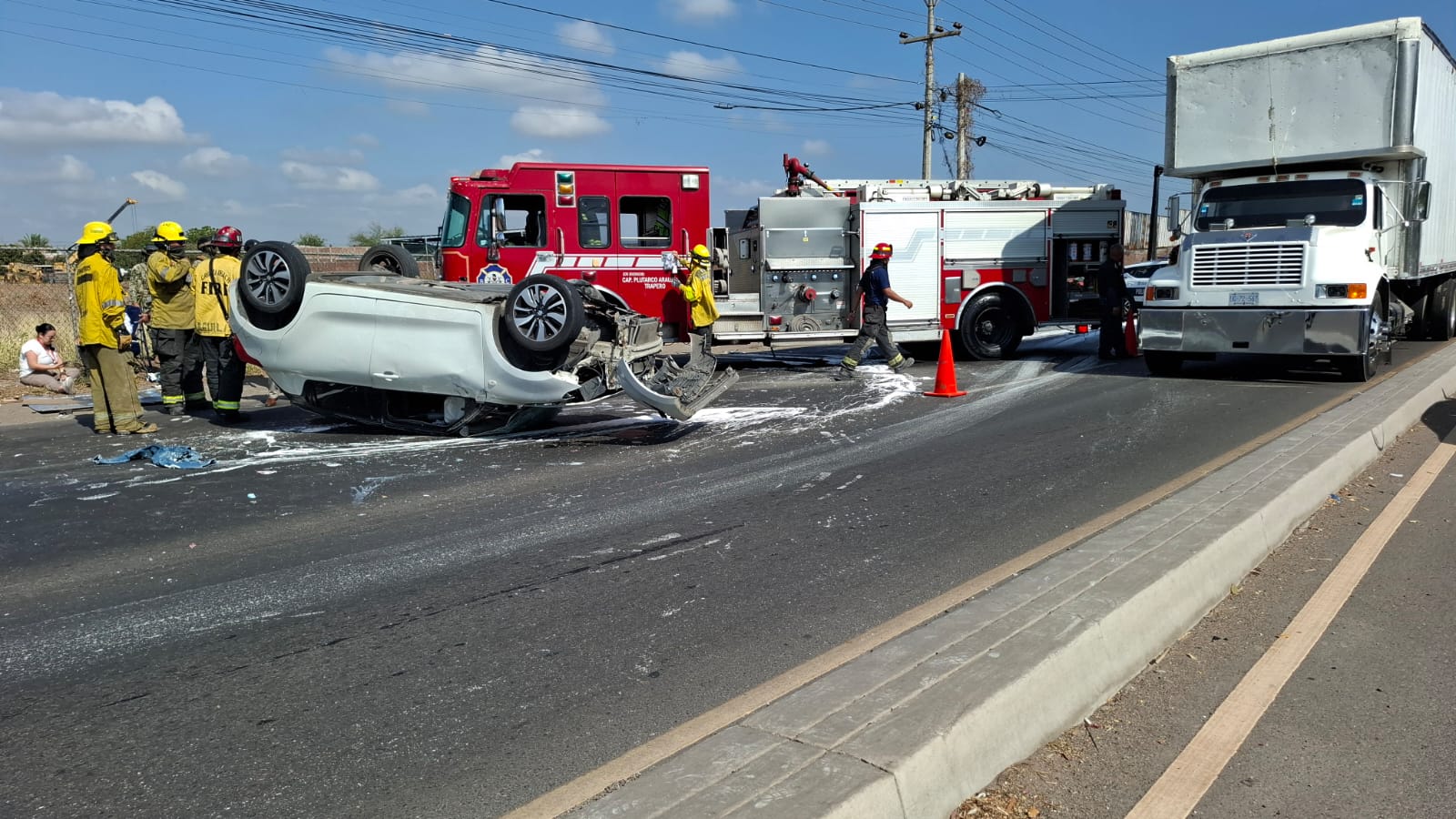 Carro volcado en carretera, unidad de bomberos y tráiler estacionados