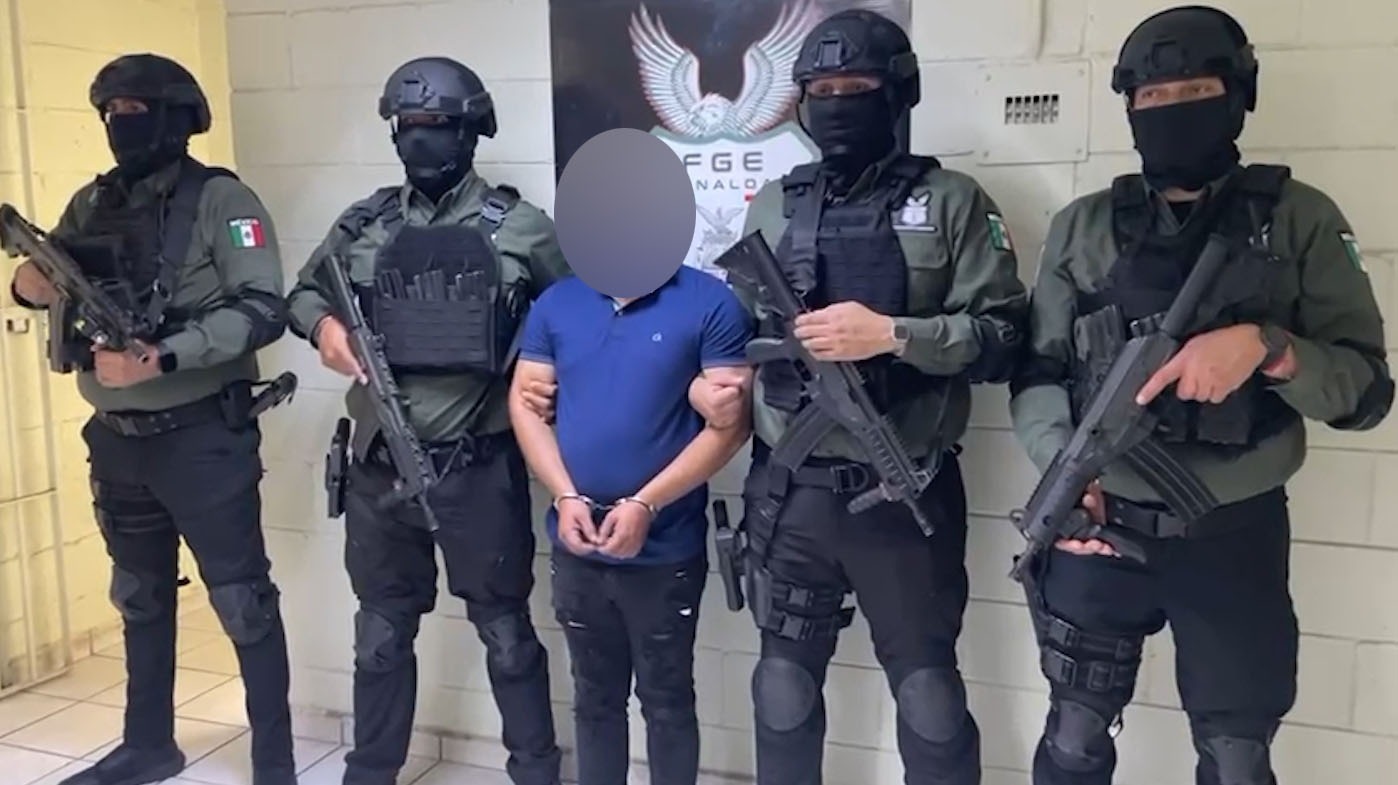 Cuatro elementos policiacos junto a una persona en el medio que fue detenida