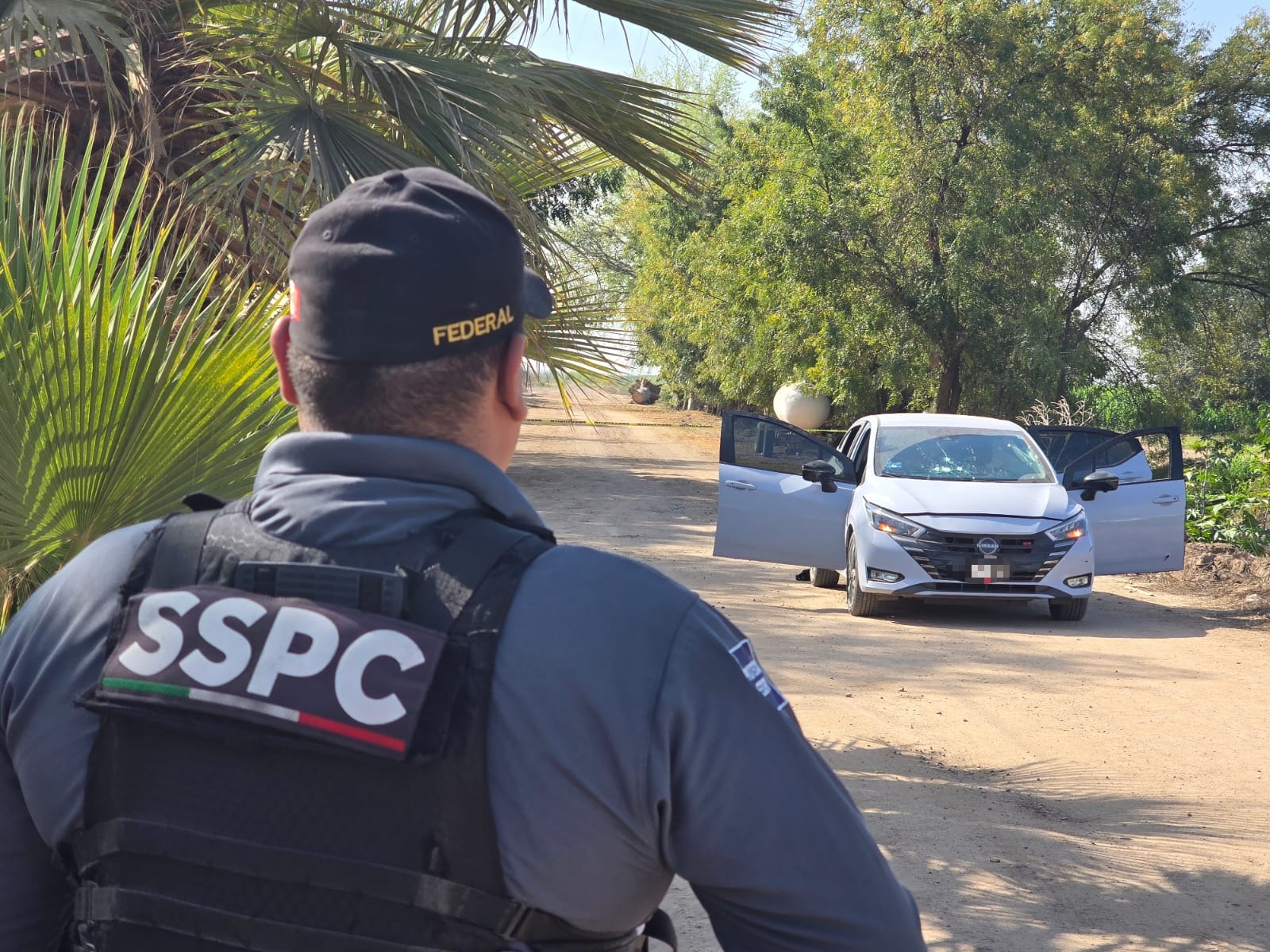 Elemento de seguridad de espaldas y en el fondo un auto baleado
