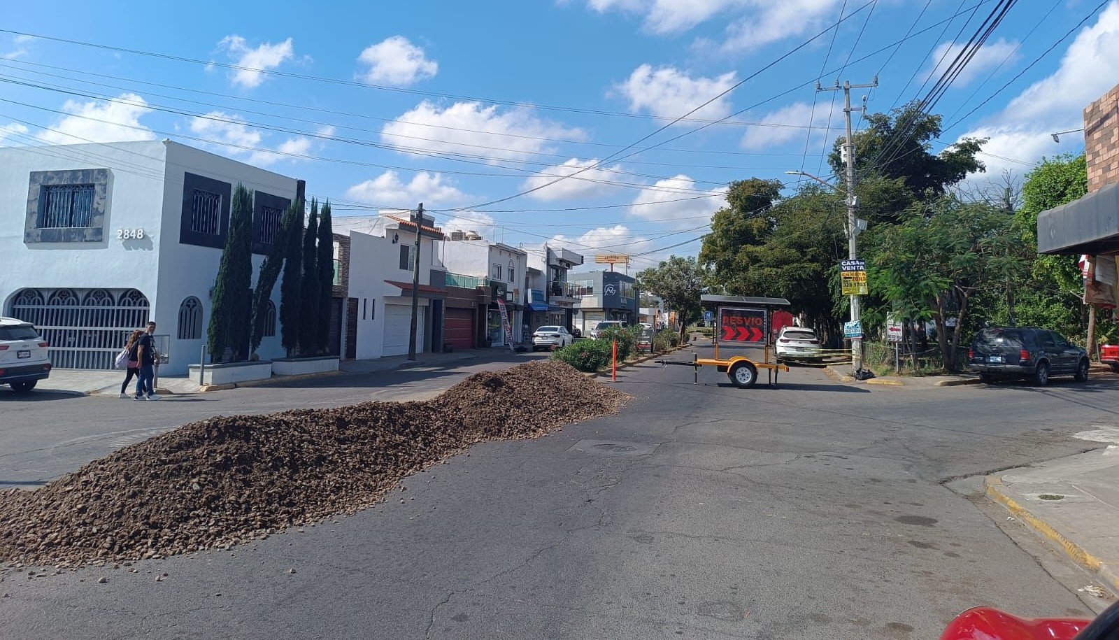 Calle de un vecindario con un bulto de tierra y una maquina que dice cerrado
