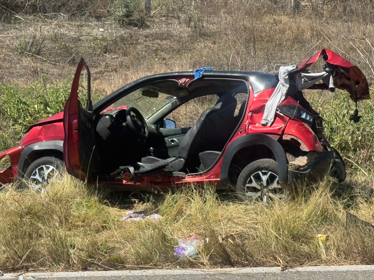 carro rojo con golpes en el asfalto luego de sufrir una volcadura