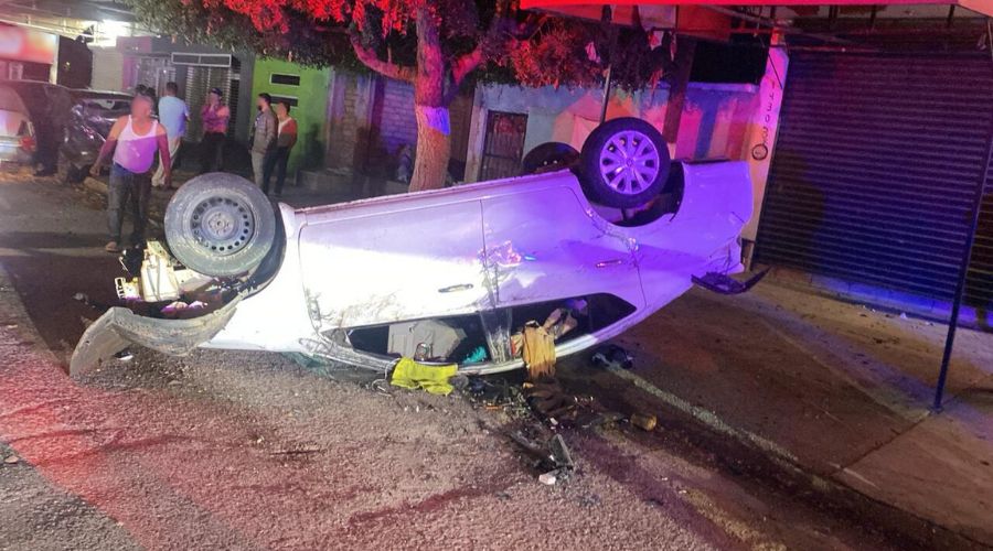 Carro blanco volteado en una calle con golpes por choque