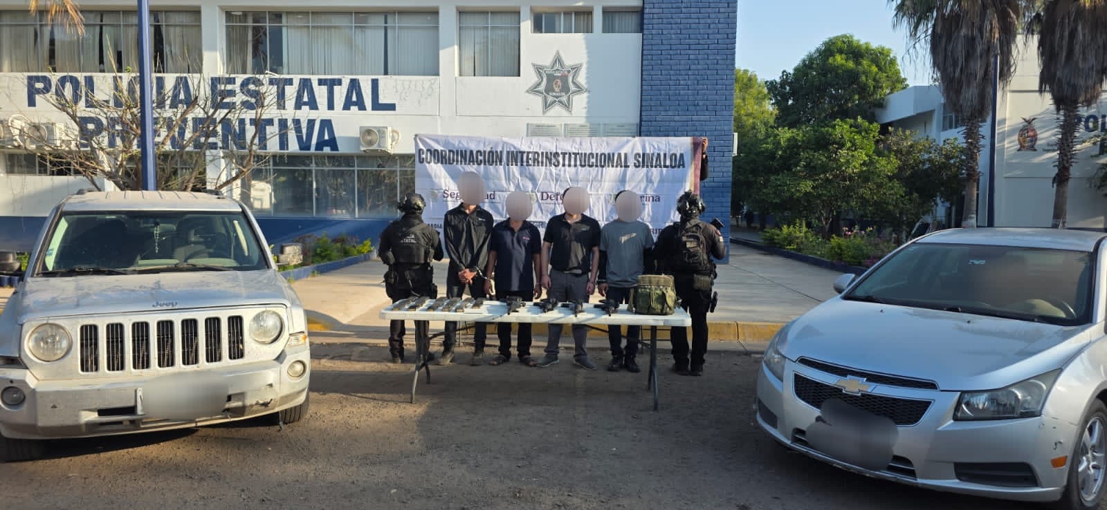 Elementos preventivos junto a hombres detenidos, dos vehículos y una mesa con armas y objetos
