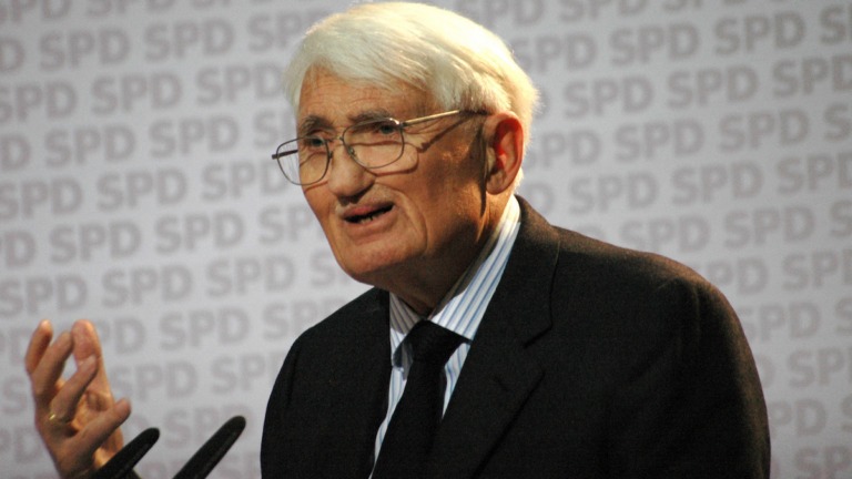 Jürgen Habermas con traje negro y la mano levantada