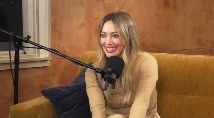 Hilary Duff sentada en una sala con un micrófono para el podcast se regalan dudas