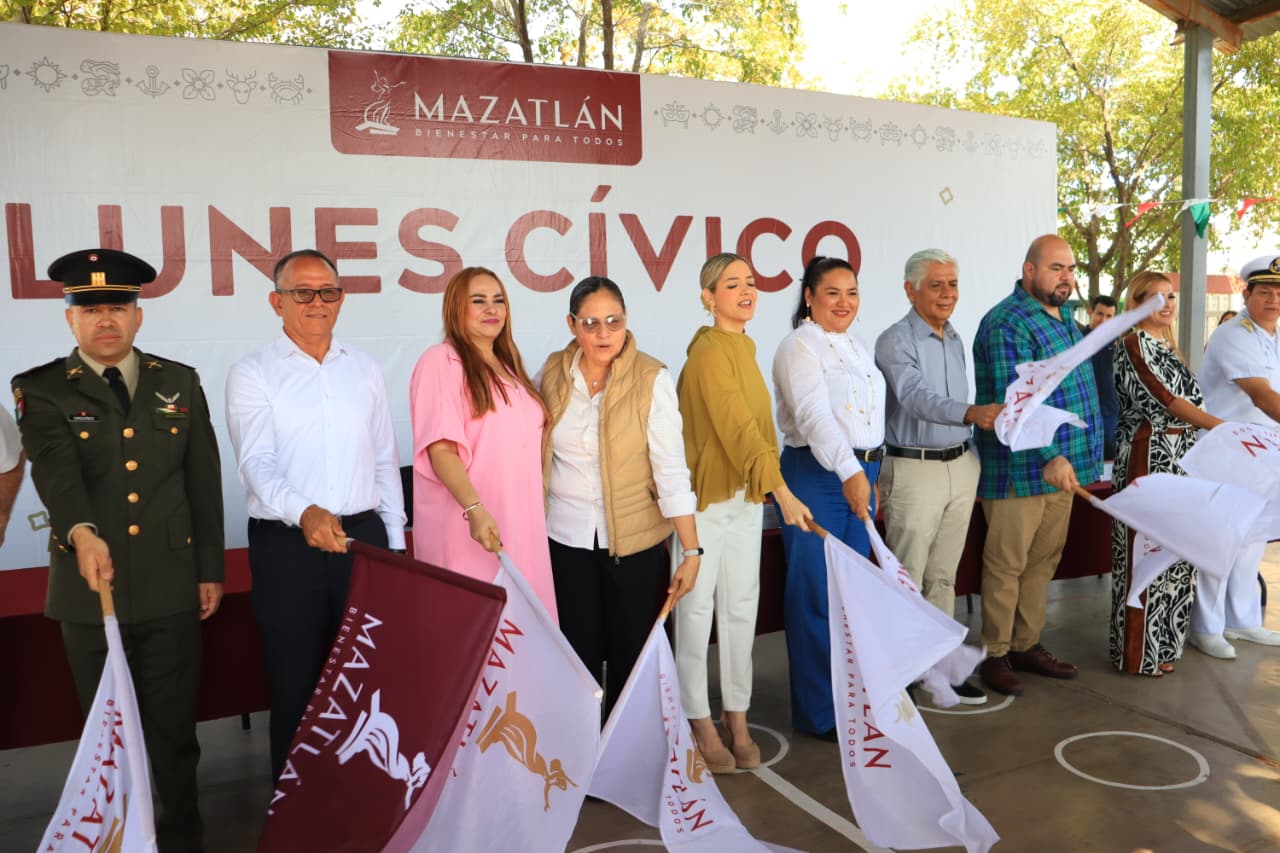 alcaldesa y personal con banderas blancas y guindas tocando el suelo