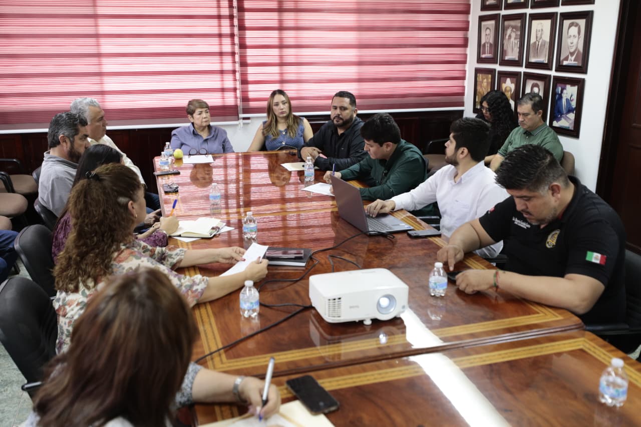Reunion de trabajo en una mesa rodeada de funcionarios