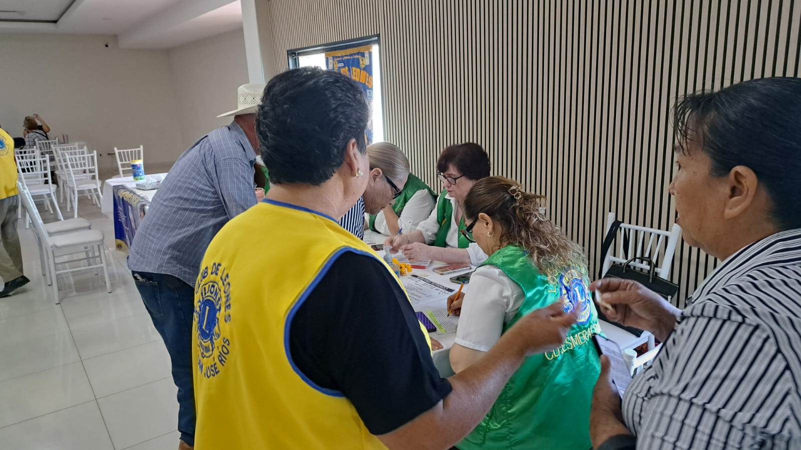 Persona escribiendo en una mesa, atendiendo a adultos